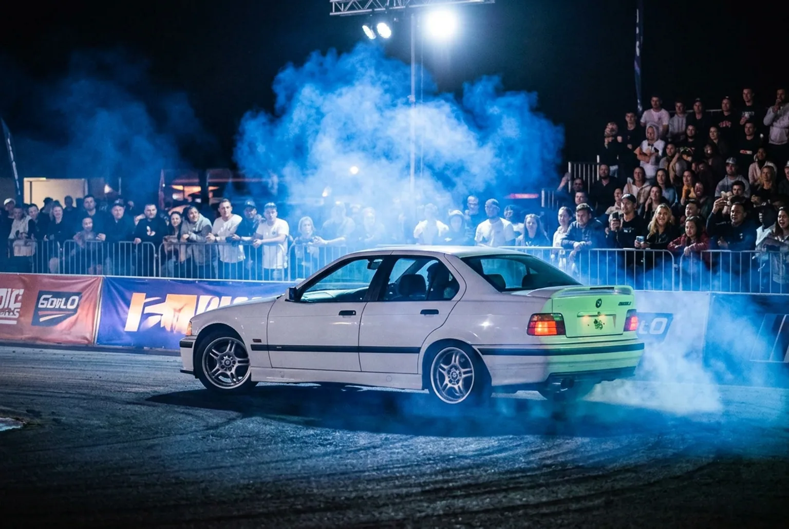 BMW E36 con humo de color de marca derrapando de noche en una activacion corporativa en Buenos Aires