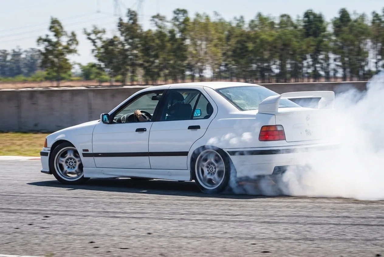 BMW E36 blanco en derrape con humo blanco saliendo de las gomas traseras en clase de drift en Buenos Aires