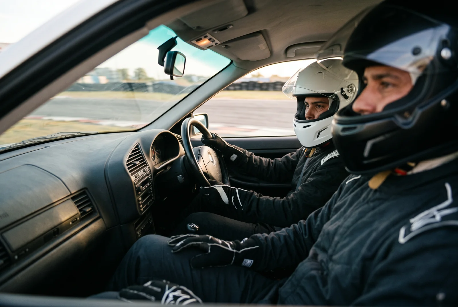 Alumno e instructor con cascos en el habitaculo del BMW E36 durante una clase de drift, coaching en tiempo real