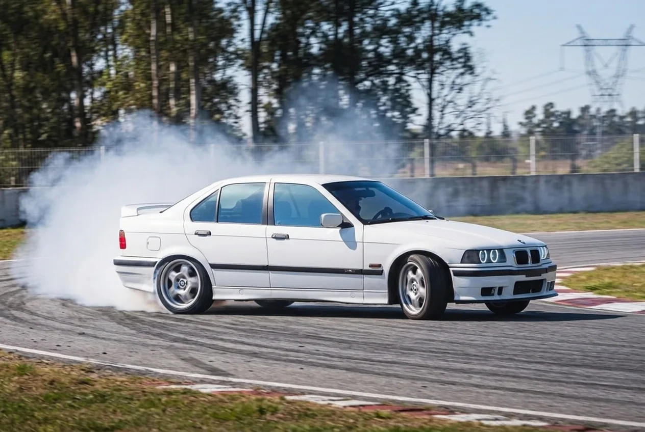BMW E36 blanco derrapando de costado con humo en las gomas en una pista cerrada cerca de Buenos Aires