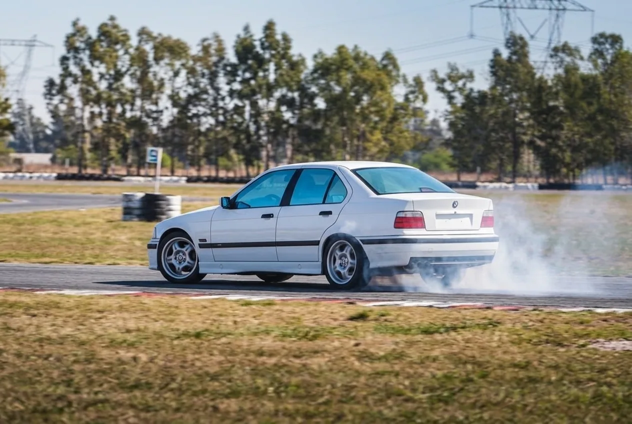 BMW E36 blanco rompiendo traccion con las ruedas traseras humeando al iniciar el derrape con clutch kick