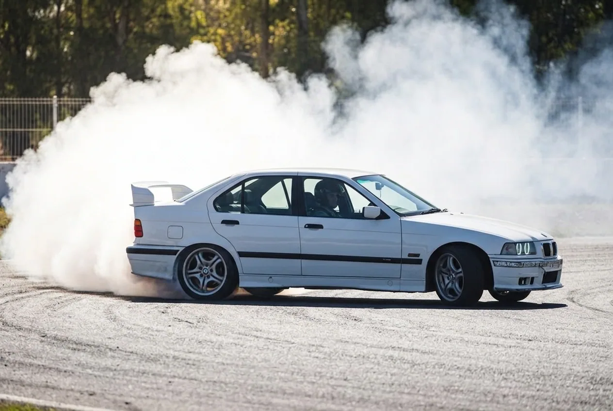 BMW E36 blanco en derrape con humo de neumaticos quemandose, experiencia de drift rara en Buenos Aires 2026