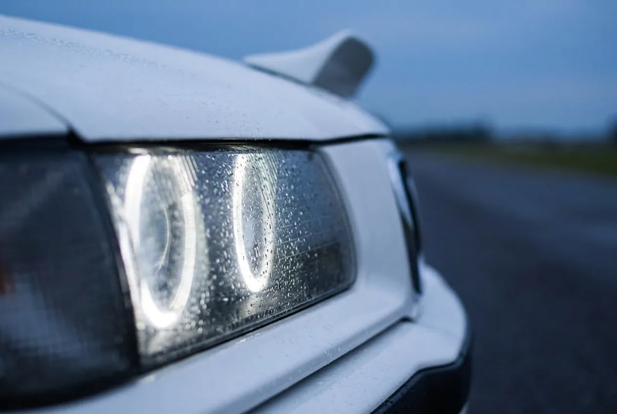 Detalle del faro angel-eye blanco del BMW E36 de drift al atardecer, mejor que un reloj caro como regalo en Buenos Aires