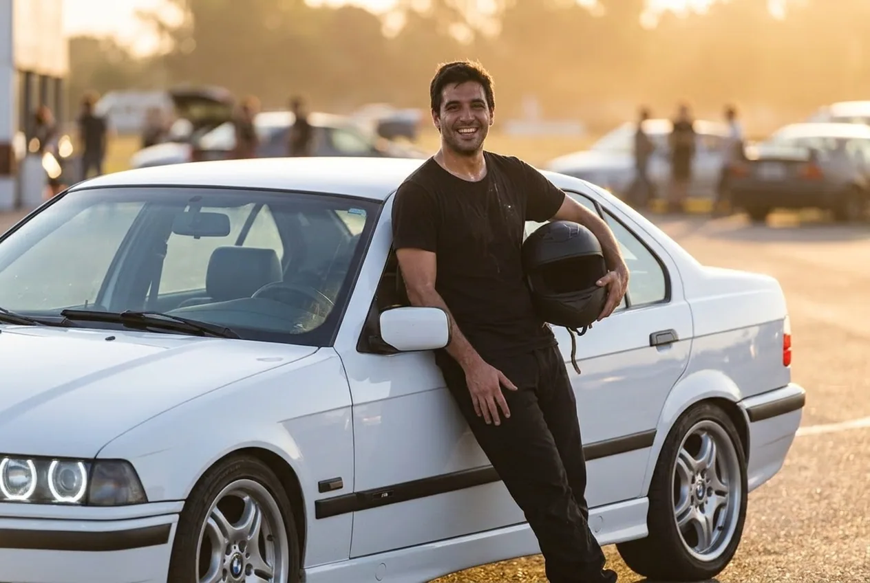 Alumno de unos 30 anos euforico apoyado en el BMW E36 blanco con el casco en la mano tras su tanda de drift