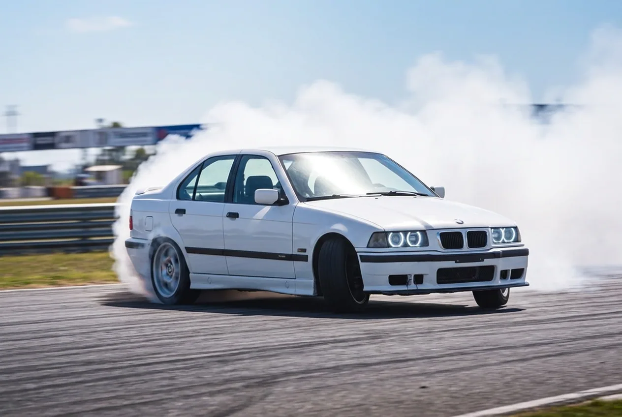 BMW E36 blanco driftando entre una gran nube de humo — la experiencia con adrenalina que si se recuerda