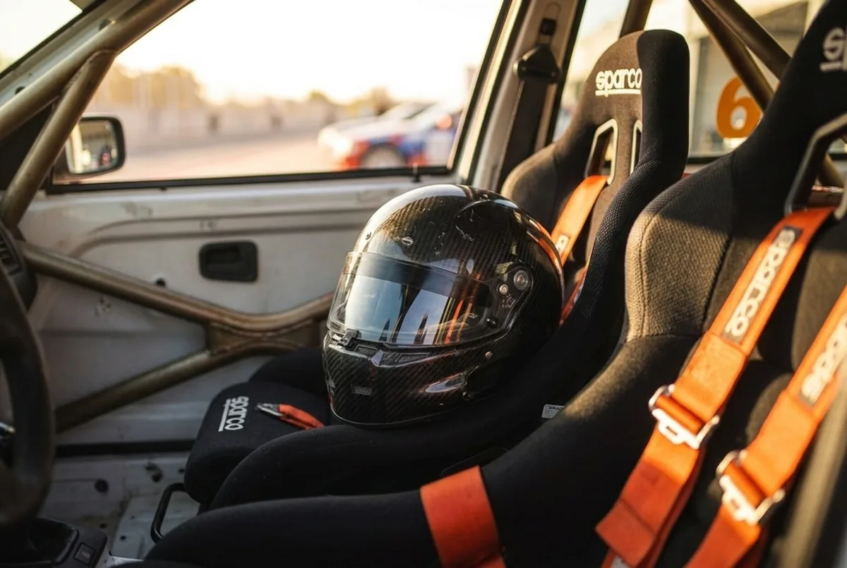 Крупный план закрытого гоночного шлема на сиденье Sparco с четырёхточечным ремнём внутри дрифт-кара BMW E36