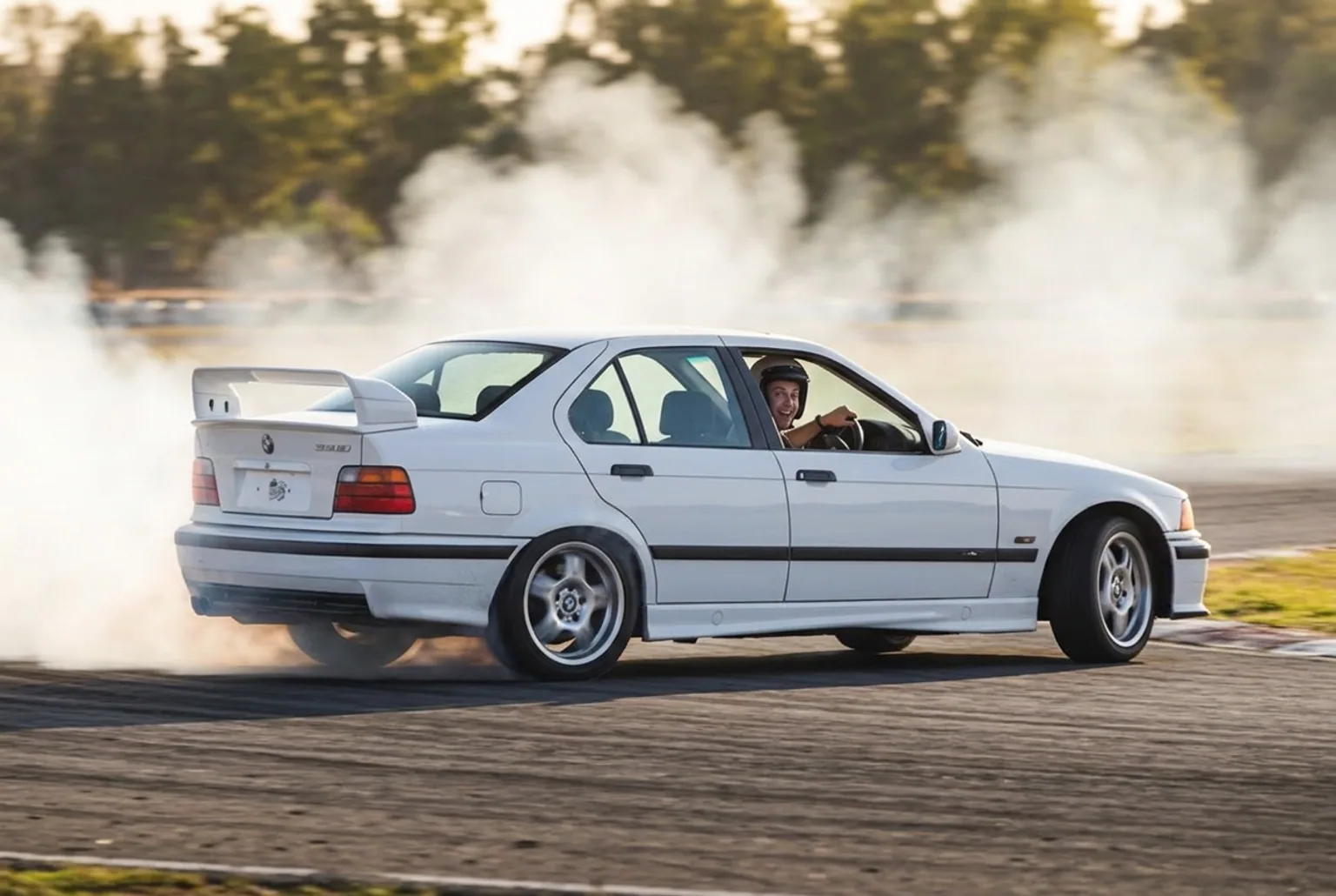 Persona comun probando drift por primera vez en un BMW E36 en una pista cerrada de Buenos Aires, humo de neumaticos