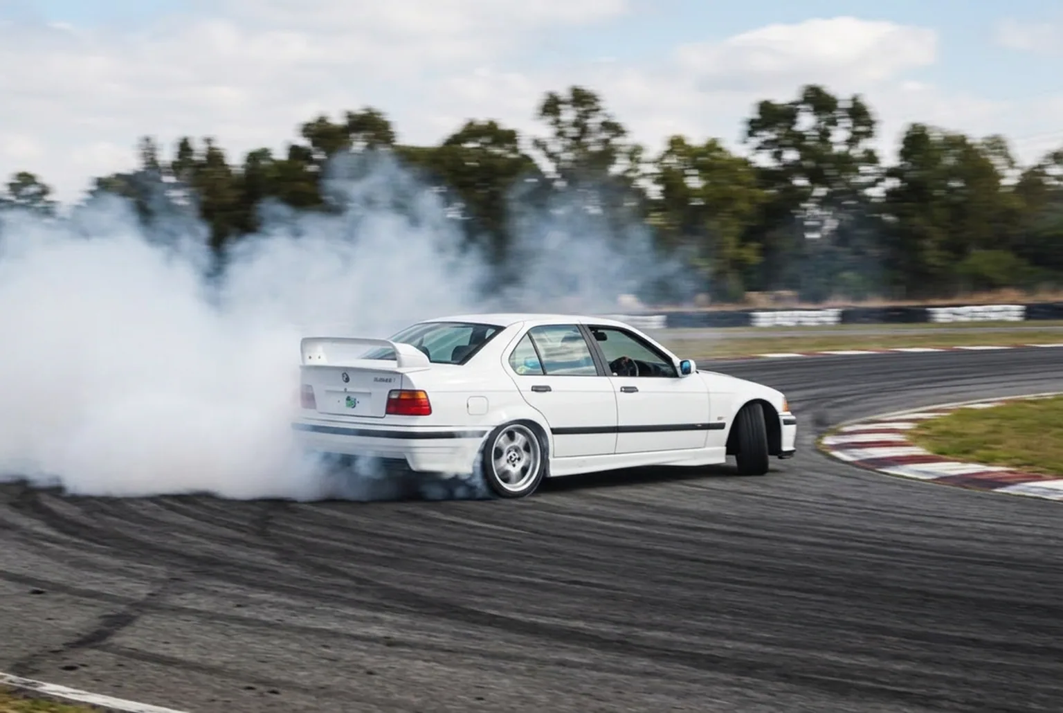 BMW E36 derrapando con humo en una curva de pista cerrada, vista desde afuera, primera experiencia de drift en Buenos Aires