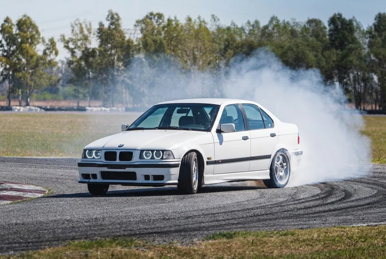 BMW E36 blanco en un derrape controlado con contravolante: el drift ensena control de acelerador y reflejos al limite