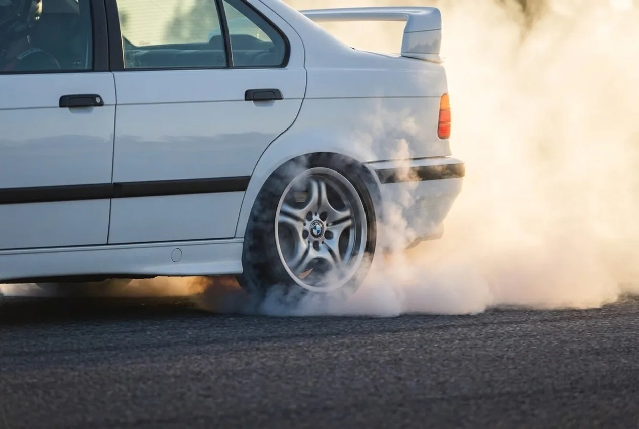 Humo blanco saliendo del neumatico trasero de un BMW E36 blanco durante una clase de drift en Buenos Aires