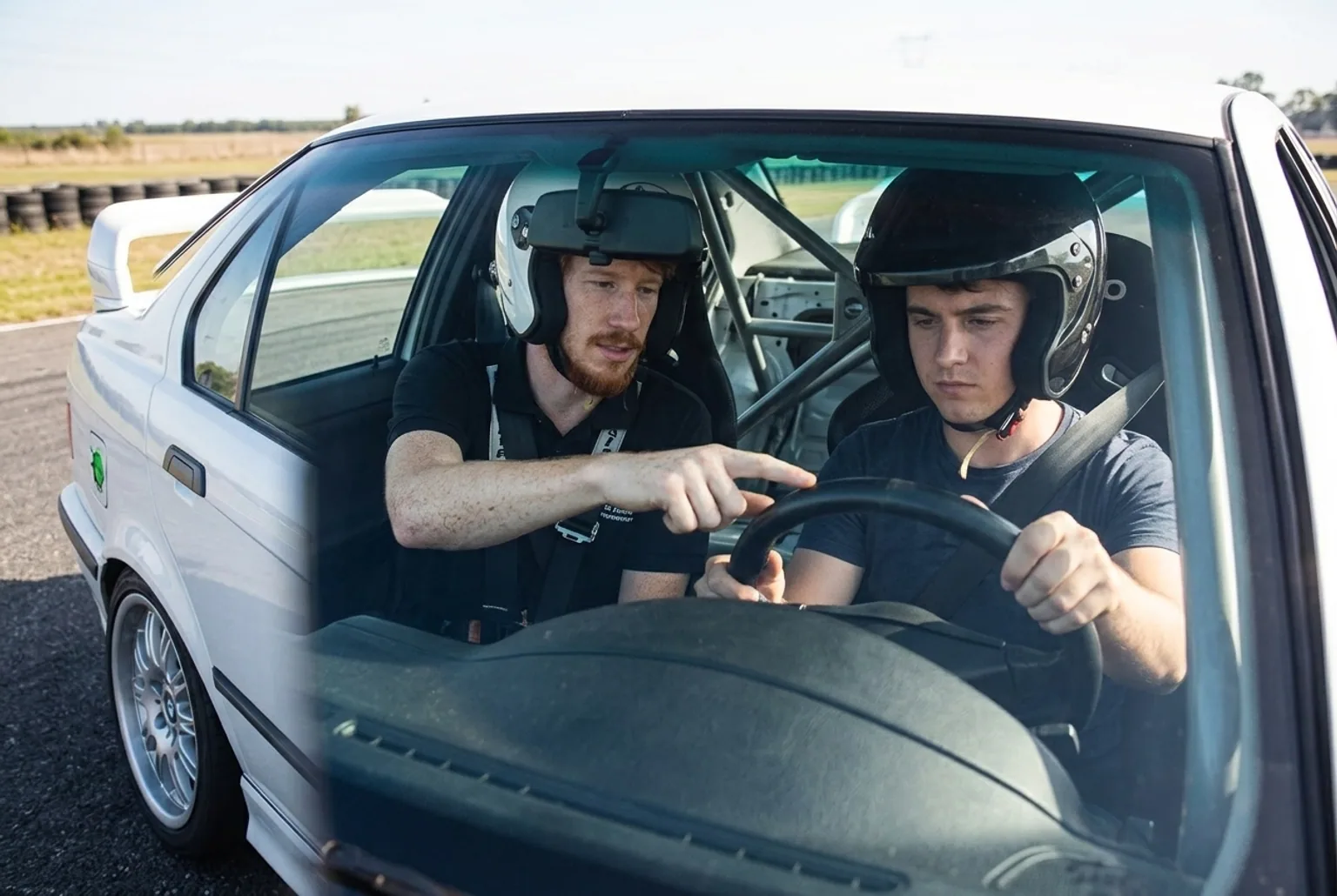 Instructor explicando el contravolante a un alumno principiante dentro del BMW E36 antes de salir a pista
