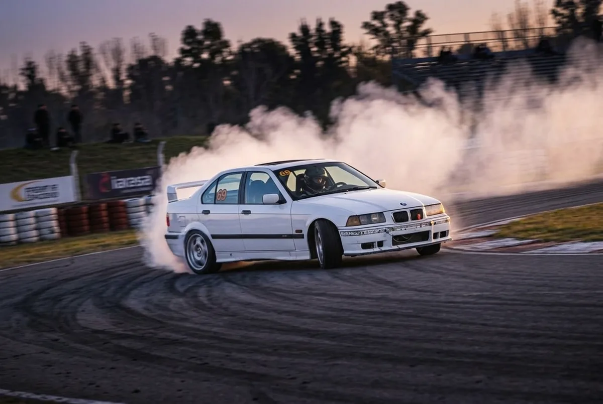 BMW E36 blanco en drift con humo en las ruedas traseras durante una jornada en autodromo argentino
