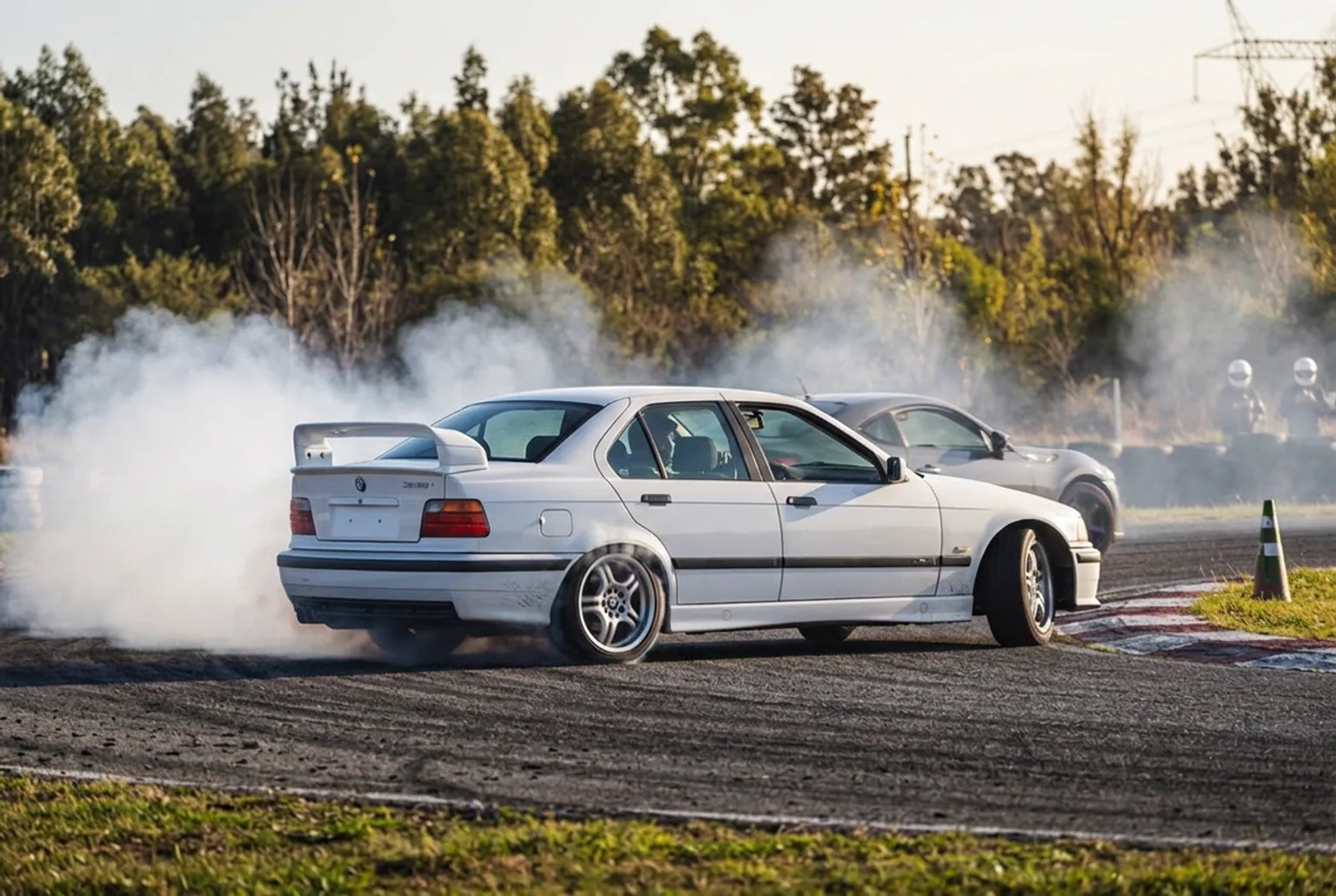 BMW E36 328i de drift cruzado en curva con humo en las gomas traseras durante una experiencia para dos en pista
