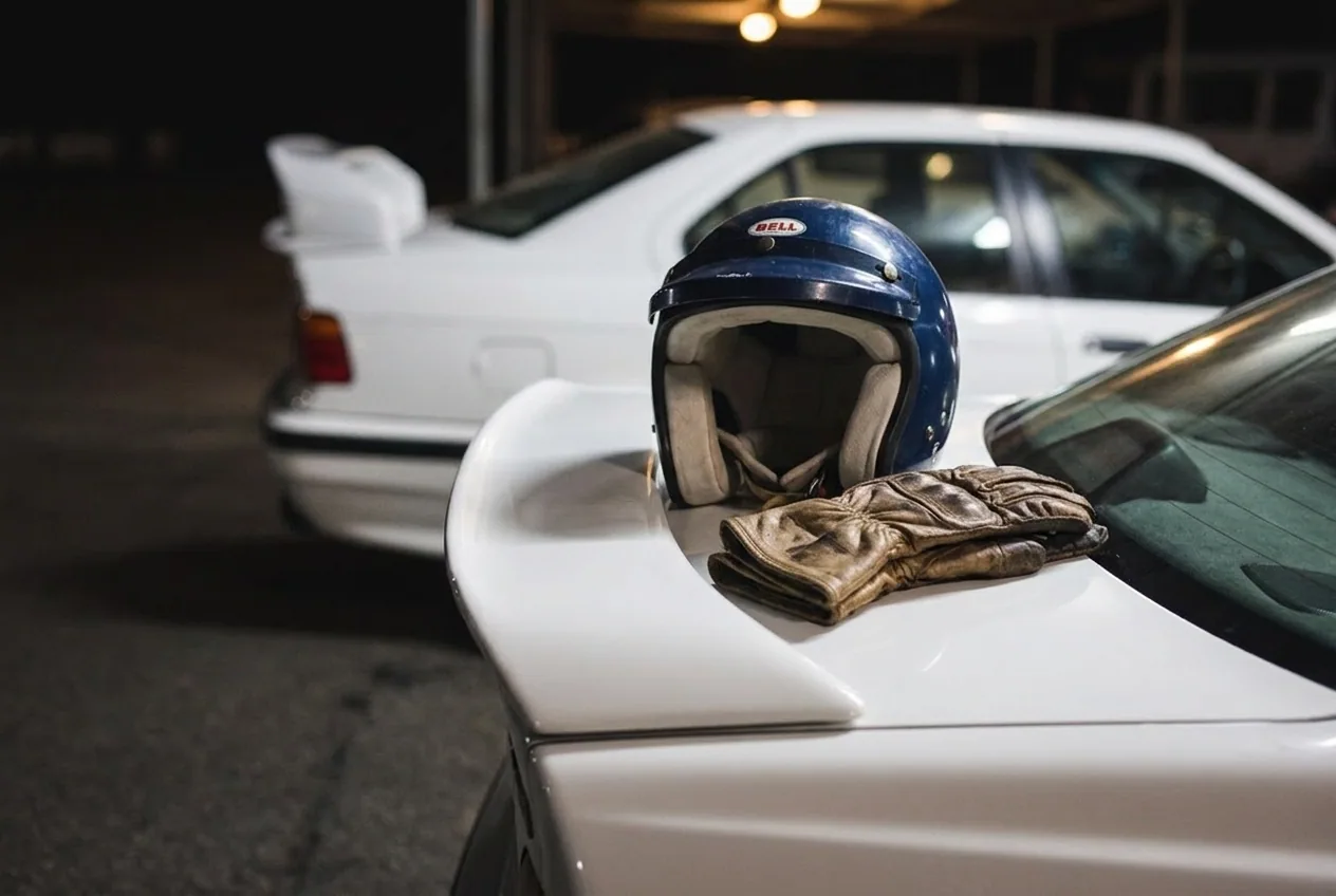 Casco y guantes de cuero racing apoyados sobre el spoiler del BMW E36, indumentaria premium como regalo para fierrero en Buenos Aires