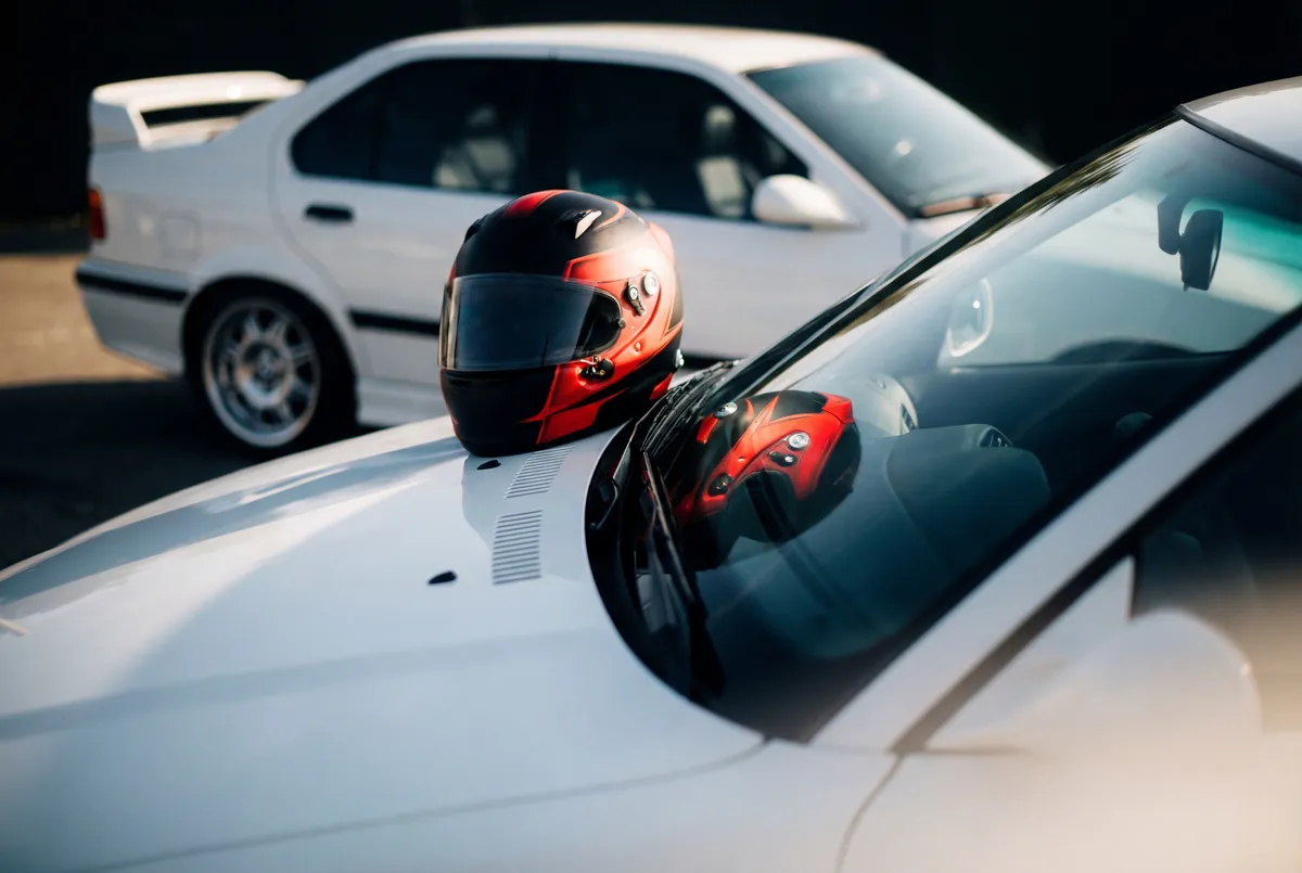 BMW E36 blanco con casco rojo profesional, simbolo de experiencia premium regalo en Argentina