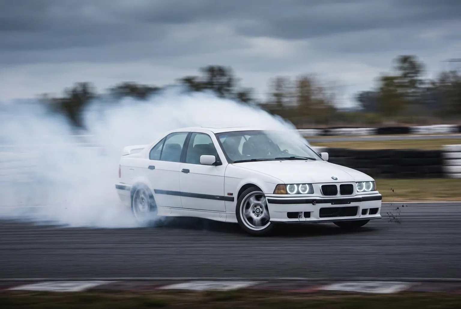 BMW E36 blanco en pleno derrape con humo de neumaticos, experiencia de drift de regalo de jubilacion en Buenos Aires