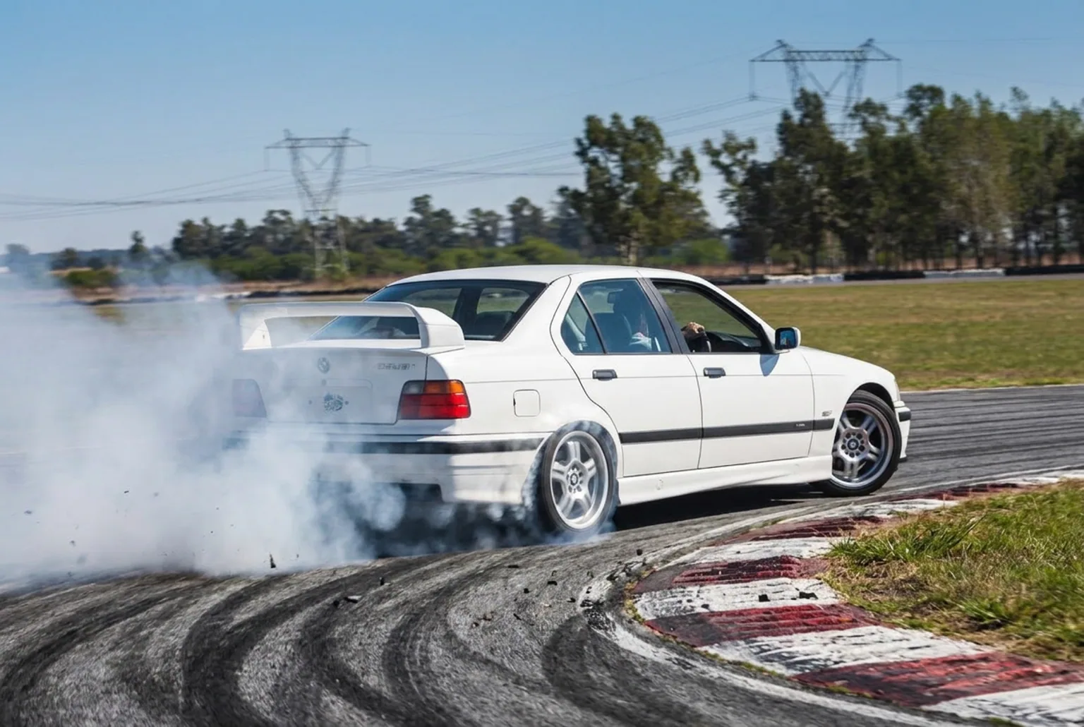 BMW E36 de traccion trasera derrapando con humo en las gomas traseras en pista cerrada cerca de CABA