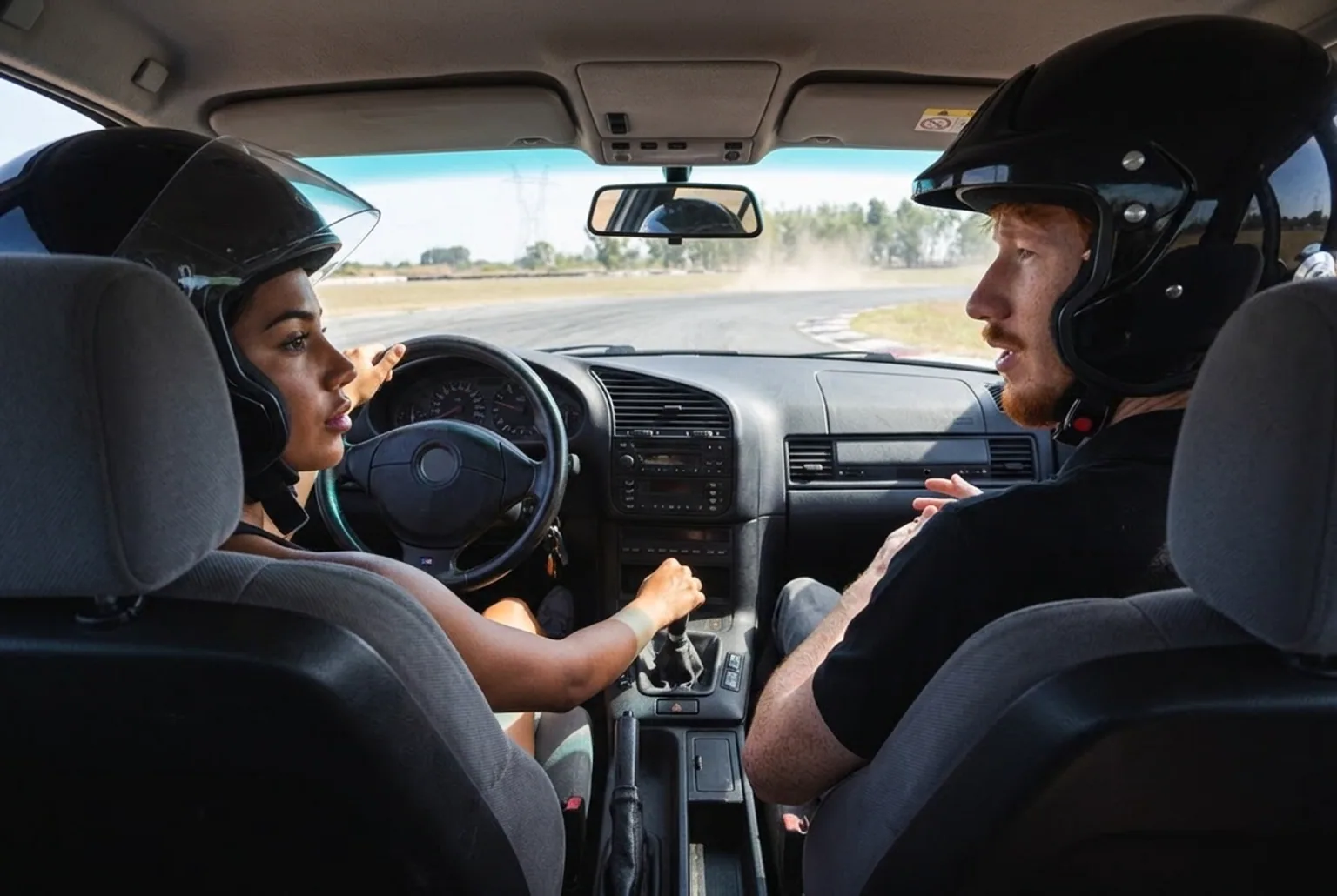 Vista interior del BMW E36 manual mientras el alumno maneja el auto deportivo con el instructor al lado en pista cerrada