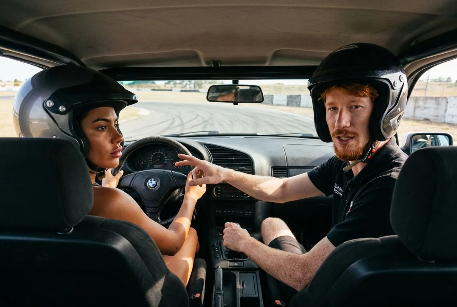 Instructor al lado de una alumna en el BMW E36 explicando el contravolante antes de iniciar el derrape en la pista