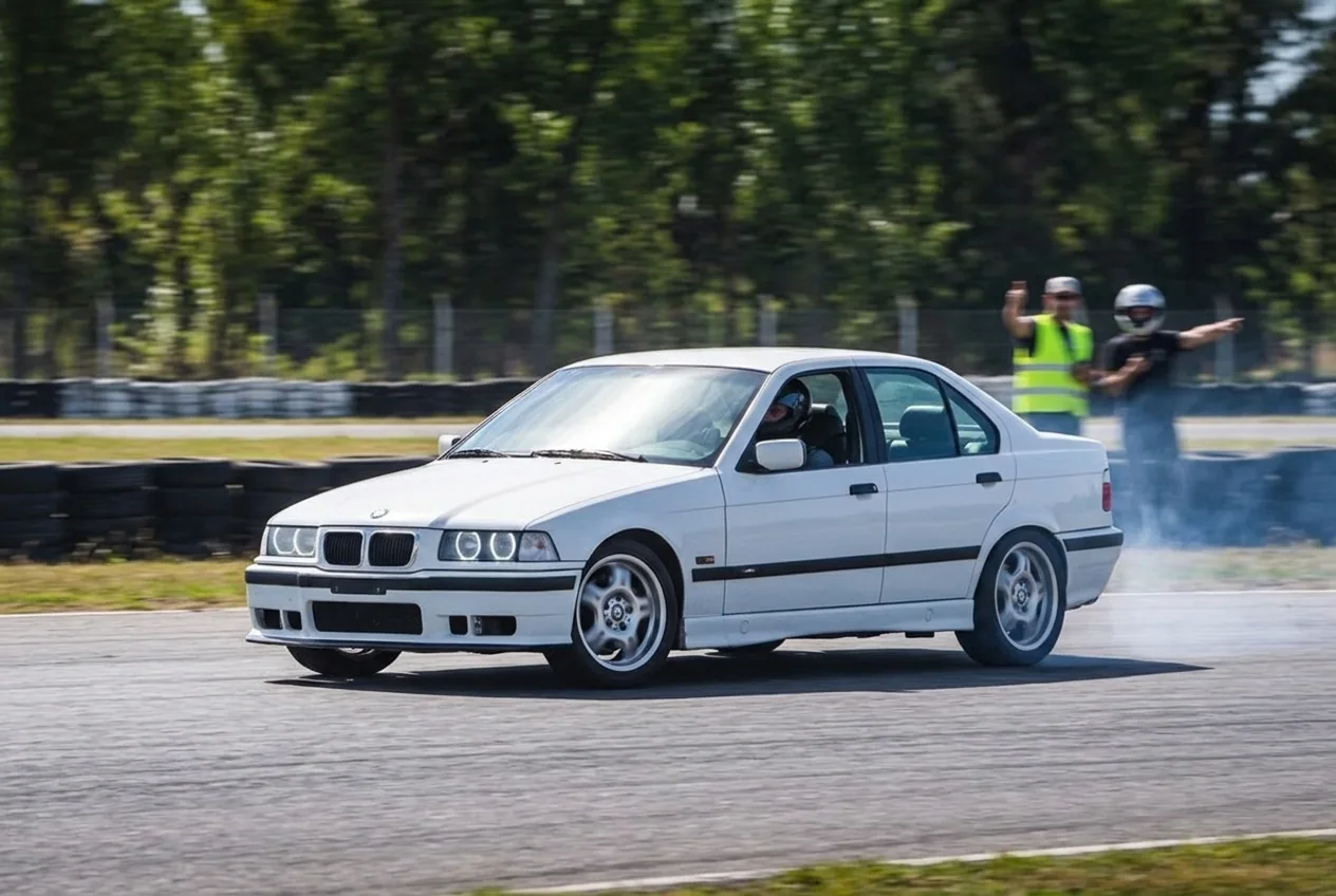 BMW E36 blanco en un primer derrape controlado de angulo suave: la progresion al final de la clase