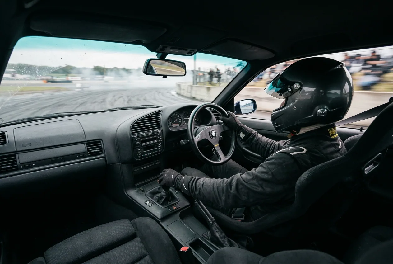 El piloto al volante del BMW E36 en pleno derrape, braceado contra la fuerza lateral: la sensacion fisica del drift