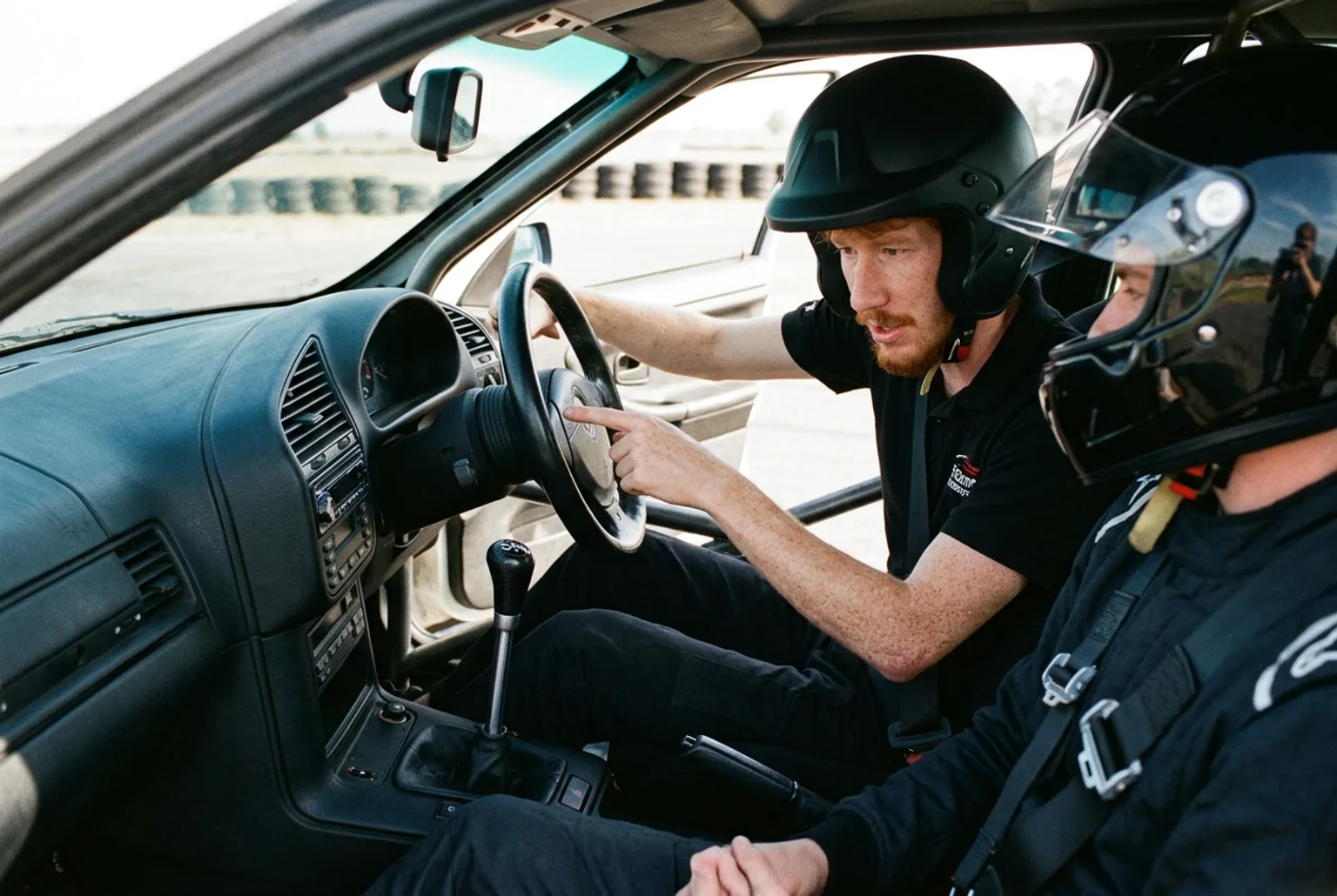 Instructor pelirrojo explicandole al alumno como tomar el volante antes de salir a la pista de drift