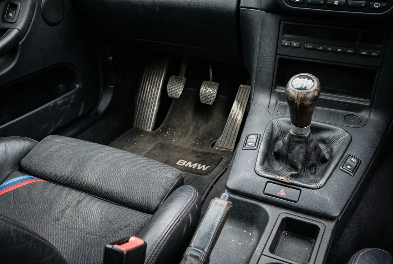 Чёрный салон белого BMW E36: рычаг механической коробки и три педали крупным планом