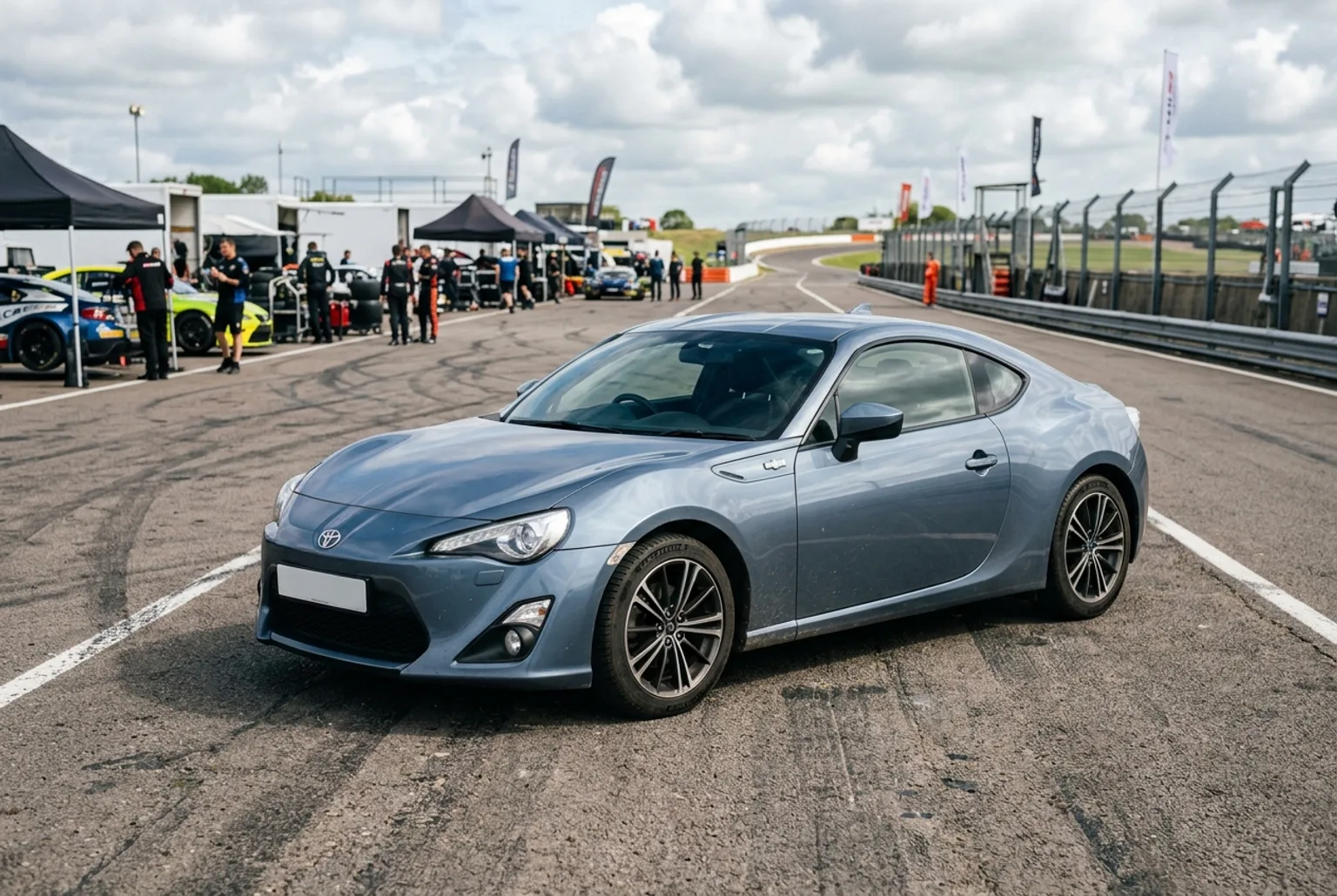 Toyota GT86 gris azulado en el pit lane de un autódromo, cupé deportivo moderno de tracción trasera