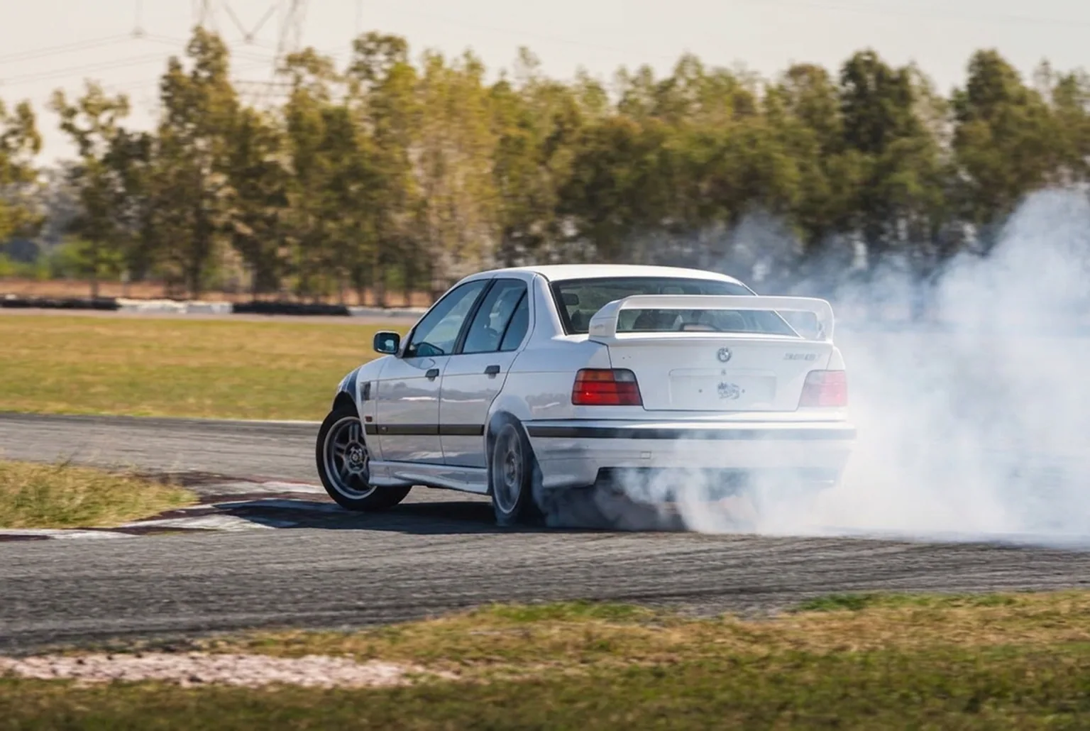 BMW E36 328i traccion trasera derrapando con humo en las gomas en pista cerrada cerca de Buenos Aires