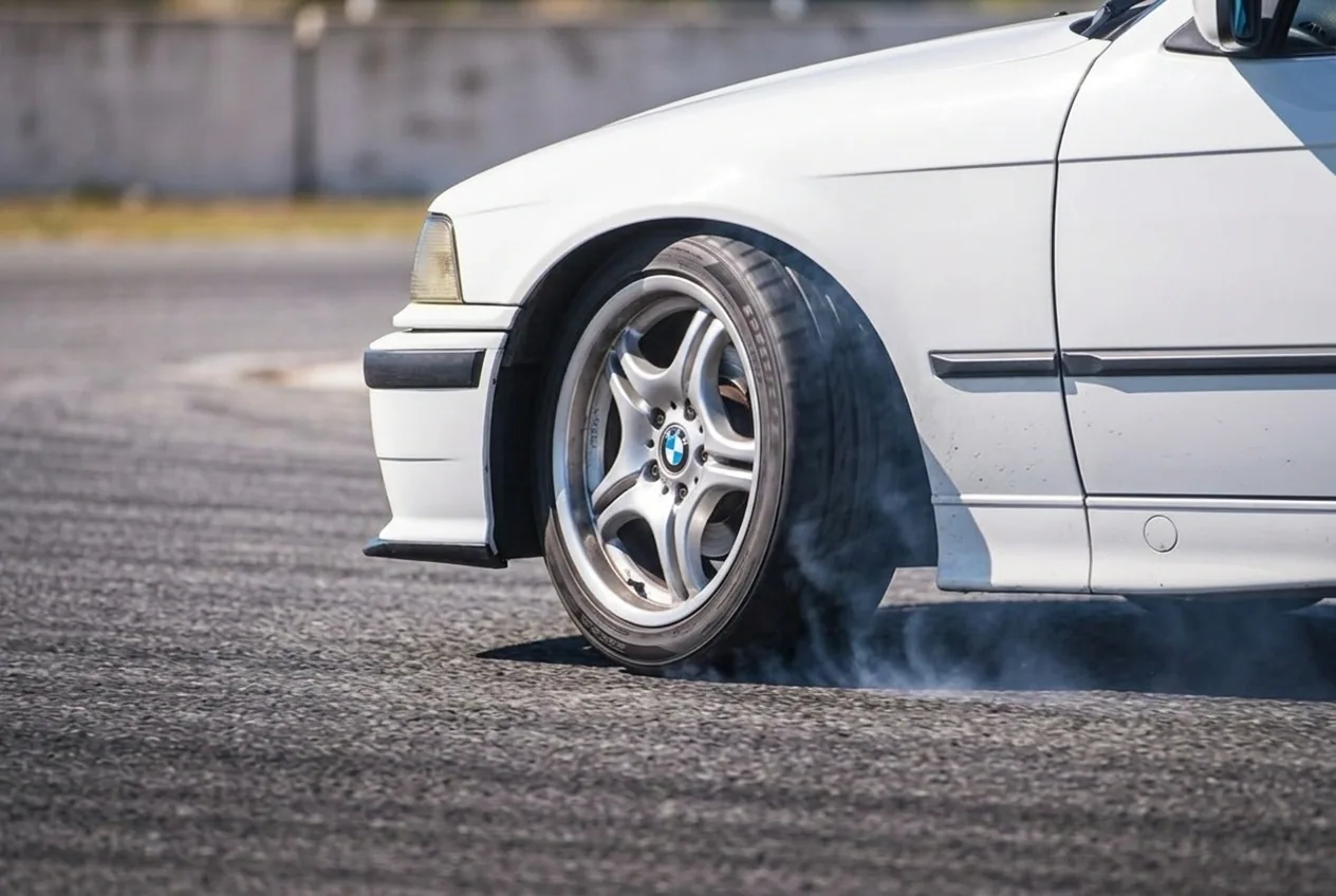 Primer plano de la rueda delantera del BMW E36 blanco girada a tope al lado contrario: eso es el contravolante