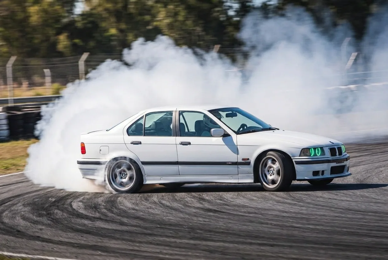 BMW E36 blanco en angulo maximo con una nube enorme de humo, estilo agresivo