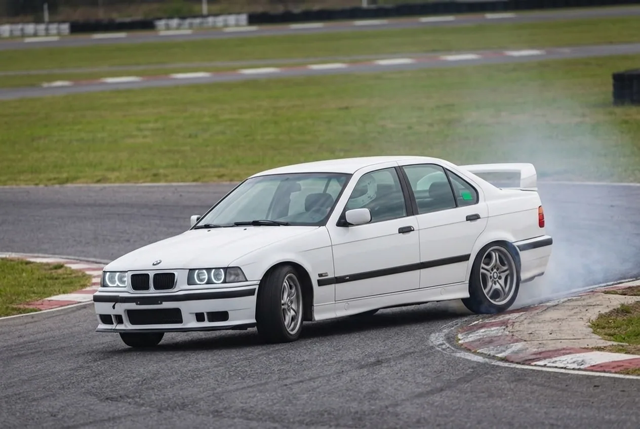 BMW E36 blanco drifteando a ritmo controlado en una pista cerrada de día, cómo es el drift real